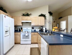 A kitchen with wooden cabinets, a white refrigerator, a stove, and a sink. - Arcade Game Night! Epic Value! Near Parks! 335 (Davenport)