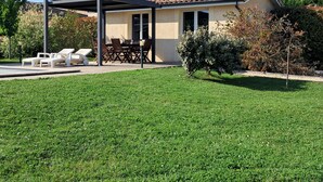 Een huis met een overdekte patio, een gazon en een tuin.