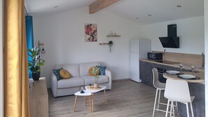 Een moderne leefruimte met een bank, een klein tafeltje, een keuken met een magnetron en een bar.