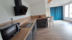 Een moderne keuken met een magnetron, een koffiezetapparaat en een bar met een stoel.