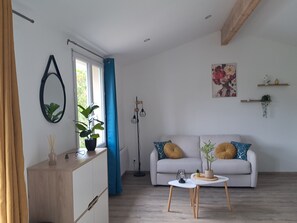 Ein modernes Wohnzimmer mit Sofa, Couchtisch, Topfpflanze, Stehlampe und einem Bild an der Wand.