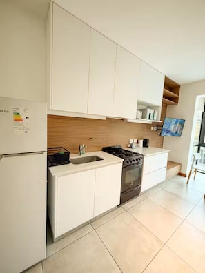 Una cocina moderna con armarios blancos, estufa integrada y un lavamanos.