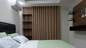 A bedroom with a bed, a headboard, a wall-mounted air conditioner, a window with curtains, and built-in shelves with decorative items. - Comfort in the best area of Santa Cruz—perfect for business travelers and tourists!! (Santa Cruz de la Sierra)
