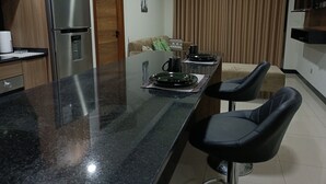 A modern kitchen with a stainless steel refrigerator, a wooden door, and a dining area with a table set for two. - Comfort in the best area of Santa Cruz—perfect for business travelers and tourists!! (Santa Cruz de la Sierra)