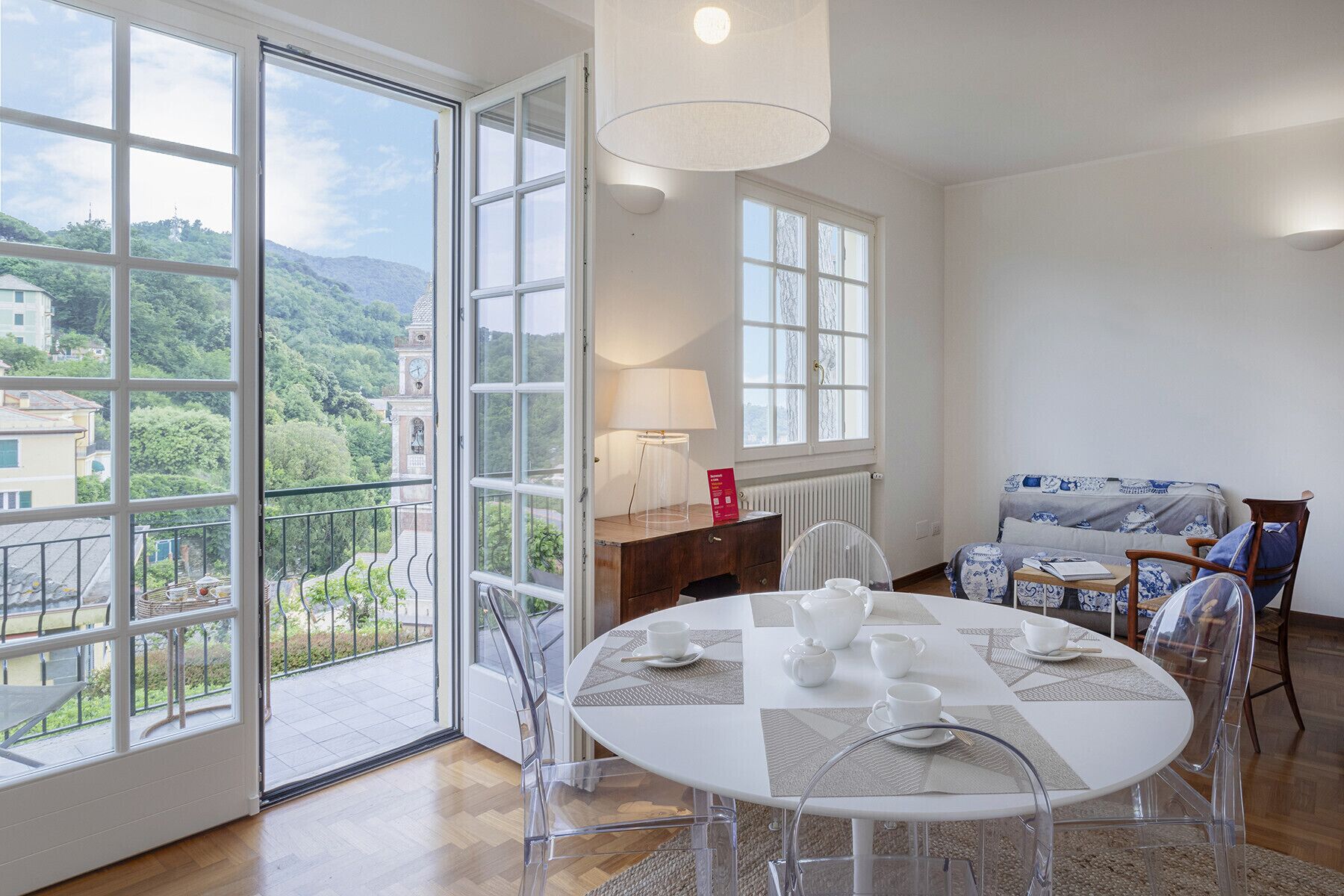 Un coin repas avec une table ronde, des chaises et une vue sur un clocher, visible à travers de grandes fenêtres.