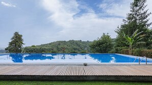 A rectangular swimming pool with a wooden deck in the foreground, surrounded by greenery and trees. - Camogli Sea and Valley View by Wonderful Italy (Camogli)