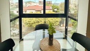 Ein Zimmer mit Glastisch, Topfpflanze und Blick auf Gebäude sowie einen Kran draußen.