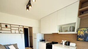 Eine moderne Küche mit weißen Schränken, einem eingebauten Backofen und einem Essbereich mit einem Glastisch und Stühlen.