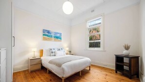 Une chambre à coucher avec un lit, des tables de chevet, une fenêtre donnant sur un beau paysage et un tableau accroché au mur.