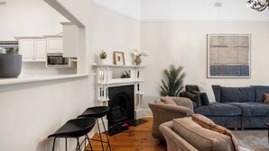 Un salon avec une cheminée, un canapé, une table basse et un coin bar avec des tabourets.