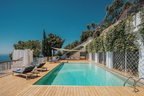 A pool area with lounge chairs, a small seating area, and a view of the sea. - Villa Allure by My Villa Collection (Ravello)