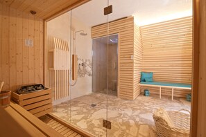 Ein Saunaraum mit Holzwänden, einer Glastür, einer Sitzbank und einem Steinboden.