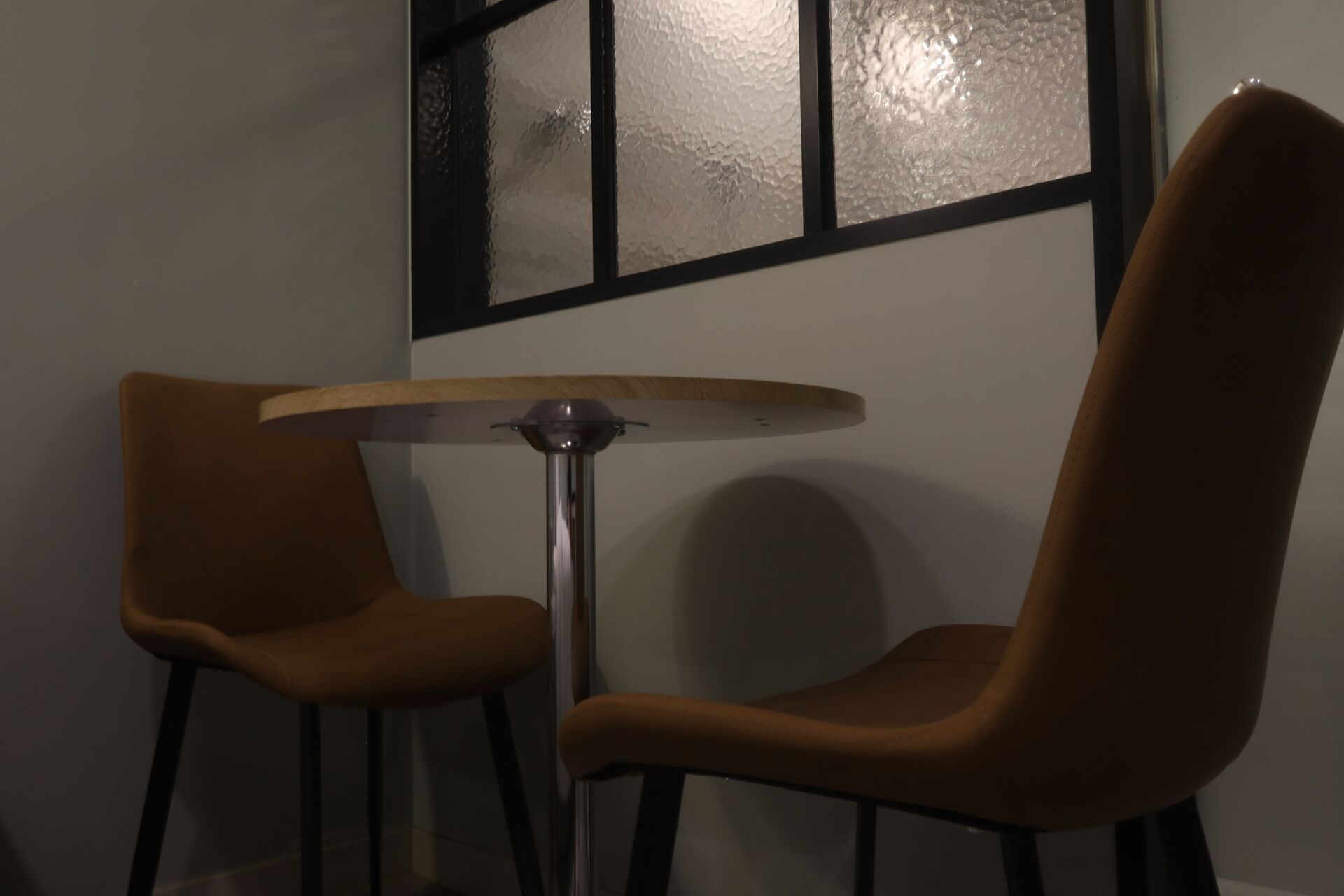 A room with two chairs, a small table, and a window with frosted glass.