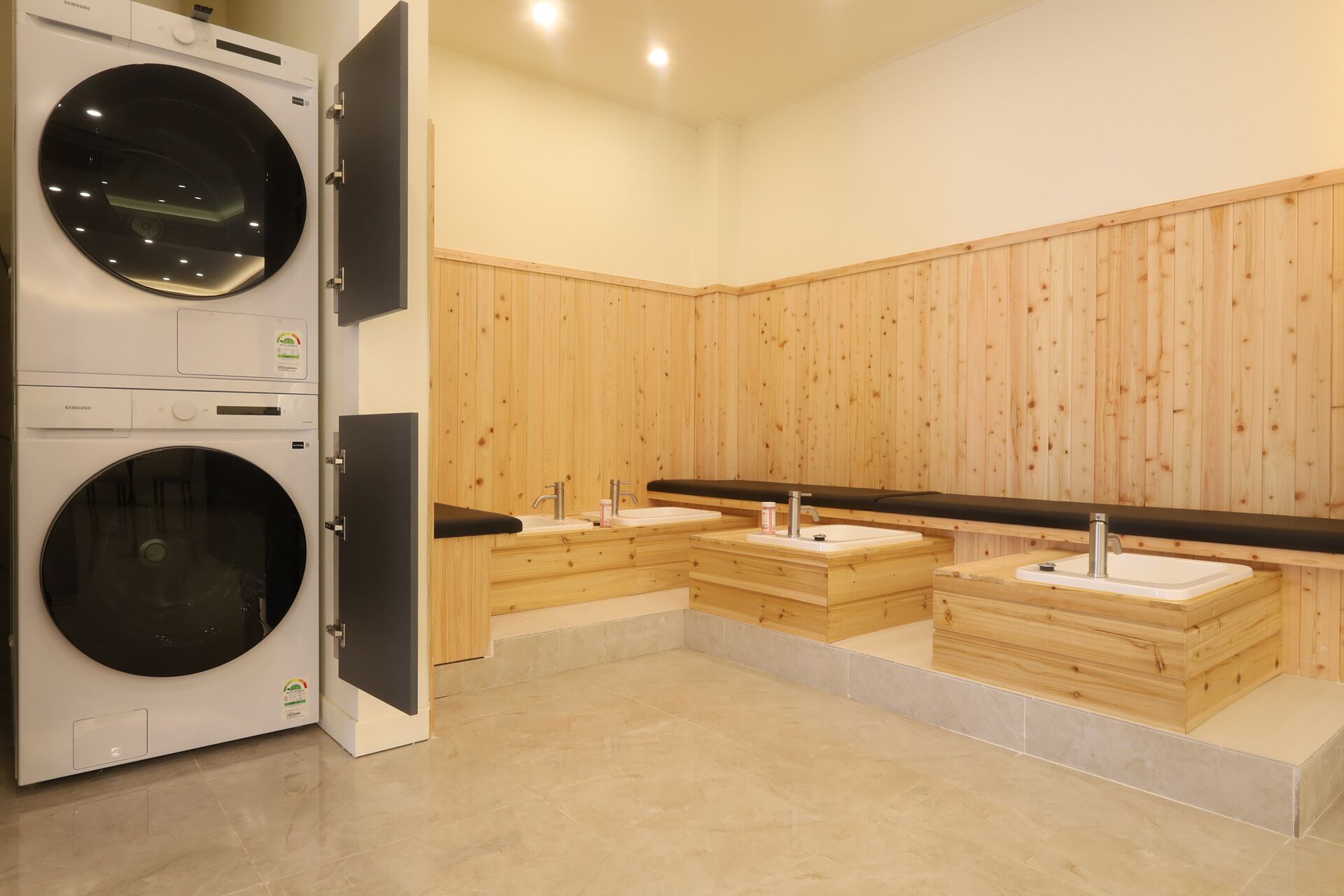 Een openbaar toilet met twee wasmachines, houten lambrisering en drie wasbakken.