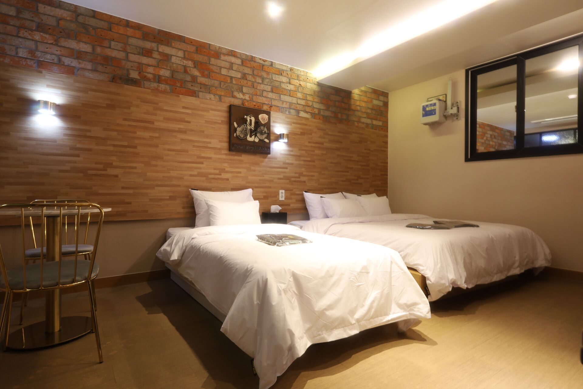 Una habitación de hotel con dos camas, una pared de madera, una ventana y una silla.