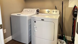 A laundry area with two front-loading washers and dryers, a hanging rack, and a Shark vacuum cleaner. - Private 2BR retreat near Zion, Shakespeare and downtown (Cedar City)