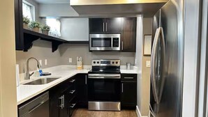 A compact kitchen with a stainless steel refrigerator, a microwave, and an oven. - Private 2BR retreat near Zion, Shakespeare and downtown (Cedar City)