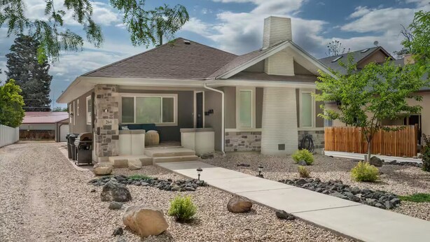 A two-story house with a stone facade, a front porch, and a gravel driveway. - Private 2BR retreat near Zion, Shakespeare and downtown (Cedar City)