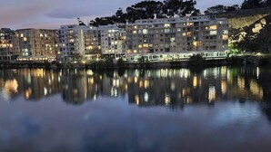 Un hotel frente al agua, con varios pisos, balcones y su reflejo en aguas tranquilas.