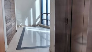 Un pasillo con suelo de baldosas, pared de madera y un ascensor metálico.