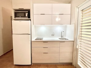 A compact kitchen with a microwave, refrigerator, sink, and cabinets. - Villa 14 Flamenco Beachfront Villas (Flamenco)