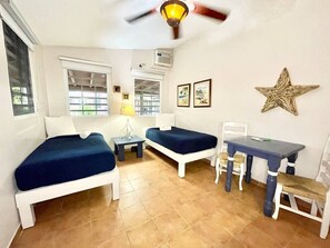 Ein Zimmer mit zwei Betten, einem Tisch, Stühlen, einem Deckenventilator und einer Stern-Dekoration an der Wand.