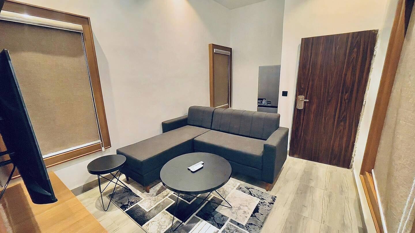 Una sala de estar moderna con un sofá seccional, dos mesitas redondas y un amplio ventanal corredero.