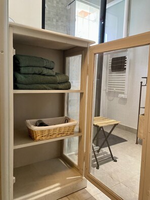 A room with a sliding glass door, a wicker basket on a shelf, and folded towels on another shelf. - House 80 m² Air-conditioned, 2 Bedrooms, 10 min. from Saint Rémy & 15 min. from Avignon (Noves)