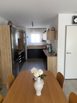 A modern kitchen with a dining table, chairs, and a vase with flowers. - House 80 m² Air-conditioned, 2 Bedrooms, 10 min. from Saint Rémy & 15 min. from Avignon (Noves)