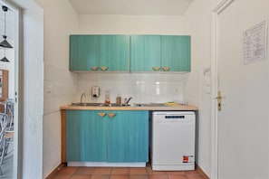Una cocina compacta con armarios color turquesa, lavavajillas blanco y salpicadero de azulejos.