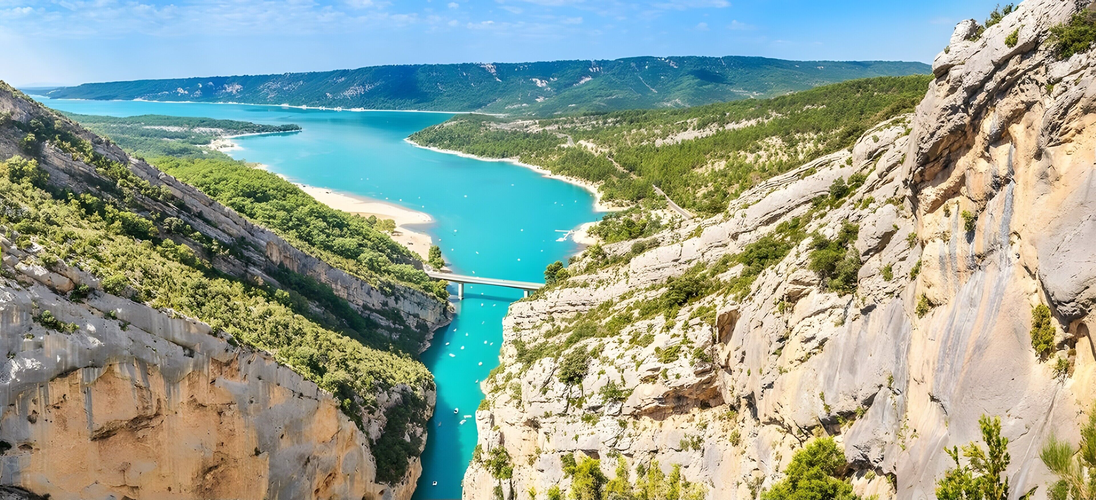 A coastal landscape with a narrow canyon, a bridge, and a turquoise sea.
