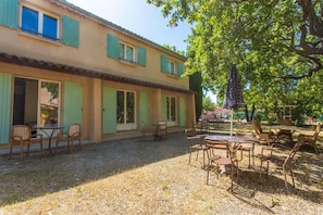 Ein Gebäude mit einer Terrassenfläche, Außenmöbeln und einer Pergola.