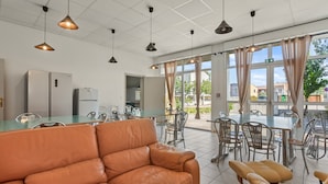 A modern kitchen with a refrigerator, dining table, chairs, and pendant lights.
