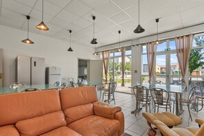 A modern kitchen with a refrigerator, dining table, chairs, and pendant lights. - La Maison des Lacs with Mountain View, Private Garden and Wi-Fi (Les Salles-sur-Verdon)