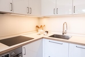Een moderne keuken met witte kastjes, een zwart aanrecht, een roestvrijstalen spoelbak en een inbouwoven.