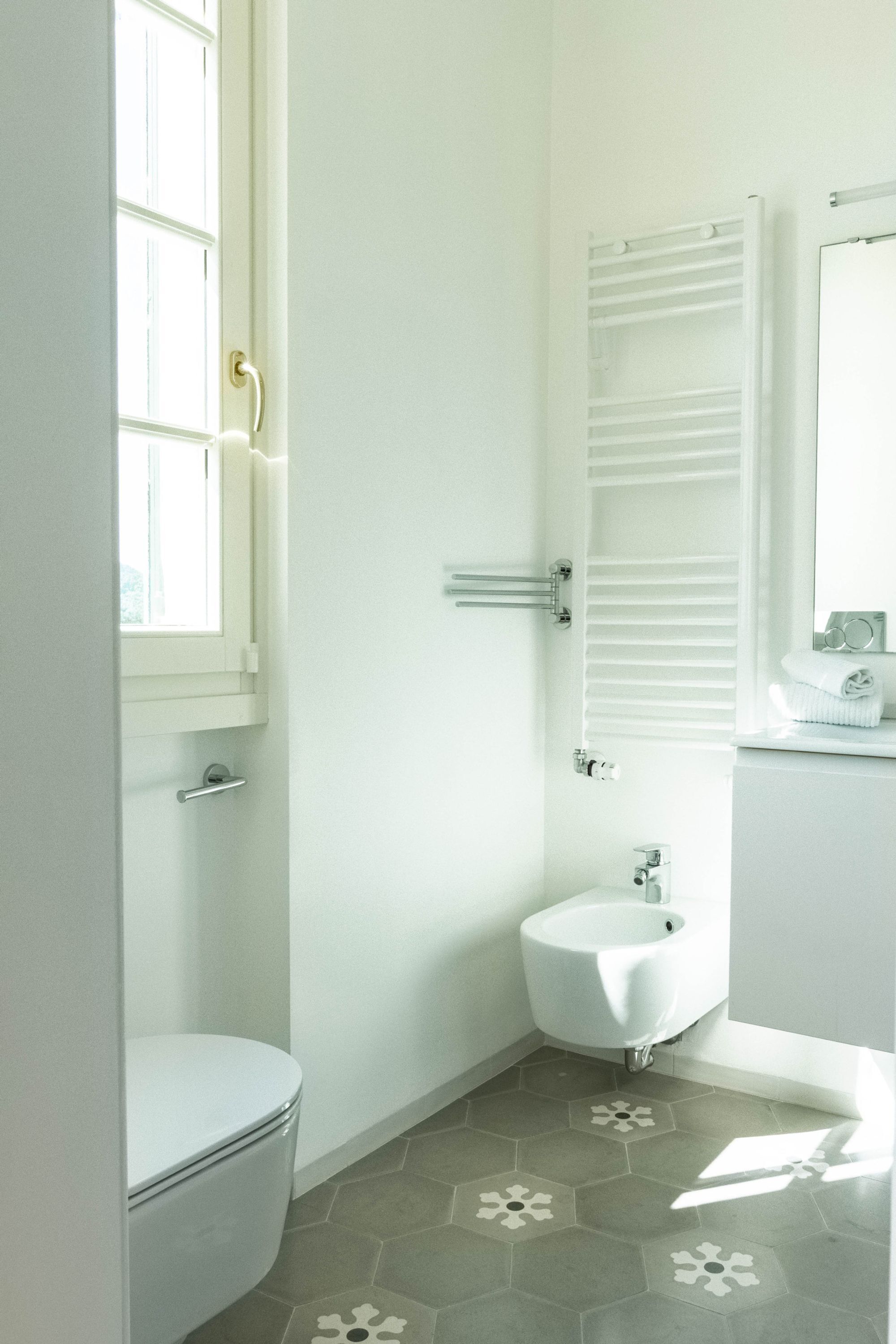 A bathroom with a toilet, bidet, and a towel rack.