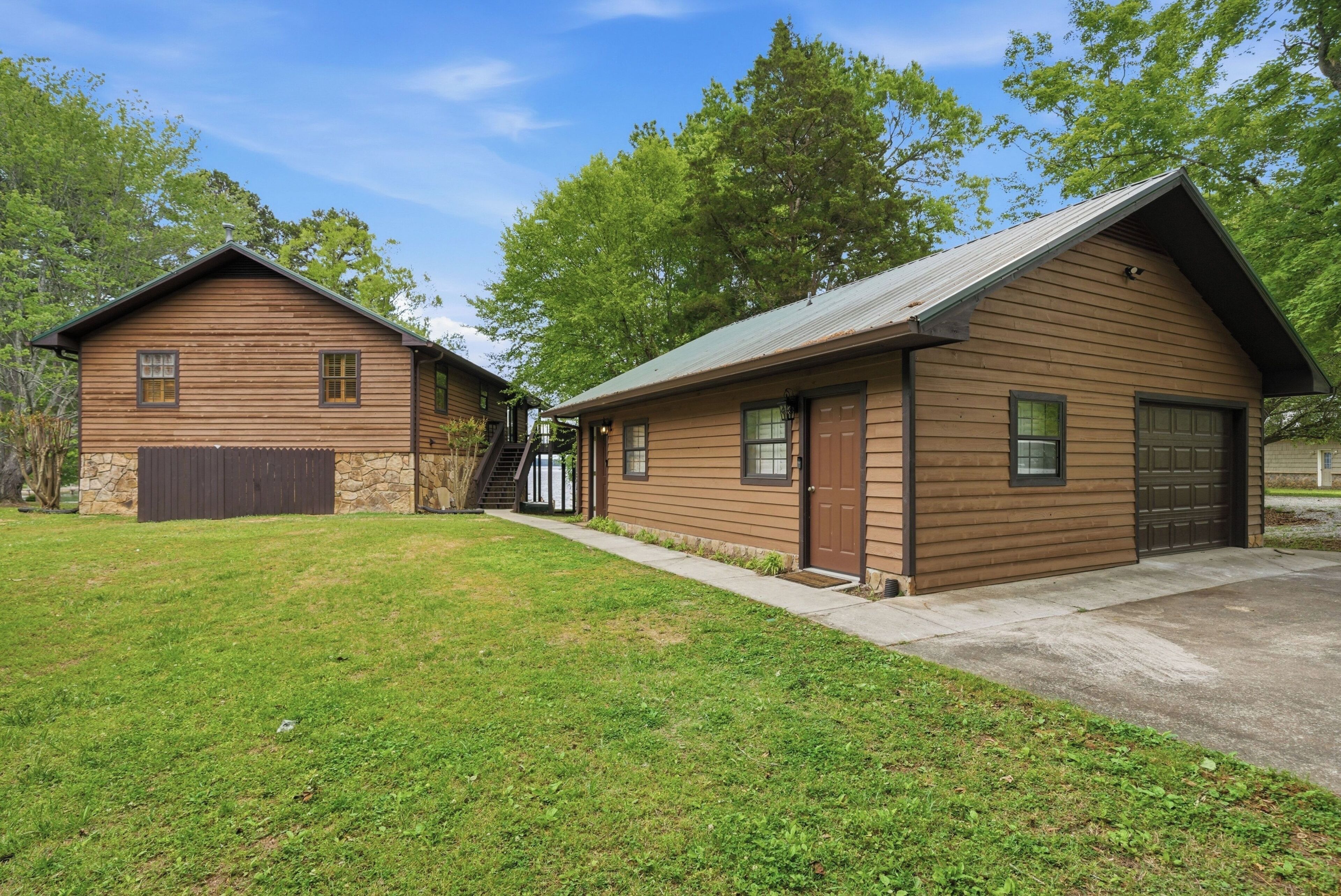 A two-story wooden cabin with a stone foundation, a garage, and a covered porch.