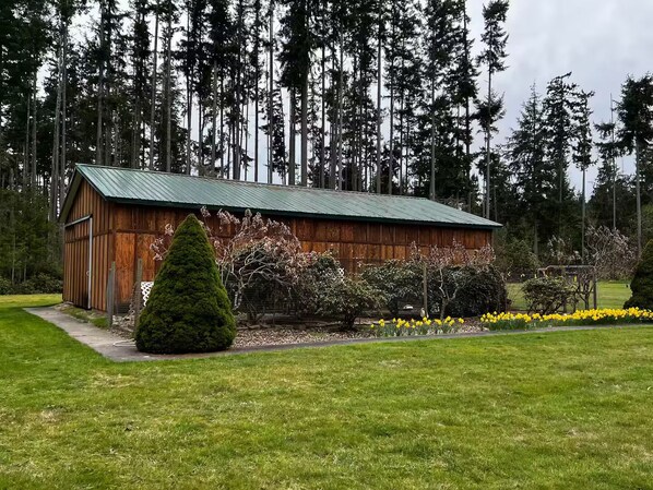 Eine Holzhütte mit grünem Dach, umgeben von einem gepflegten Rasen und blühenden Pflanzen.
