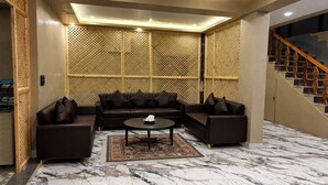 A modern living room with a sectional sofa, a coffee table, and a patterned rug. - Hotel Mustard INN Pahalgam (Anantnag)