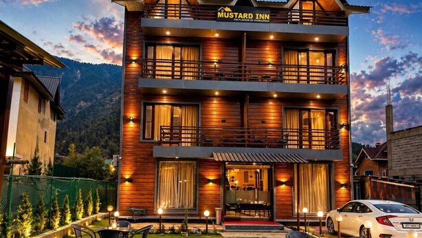 A two-story hotel with a wooden facade, balconies, and outdoor seating. - Hotel Mustard INN Pahalgam (Anantnag)