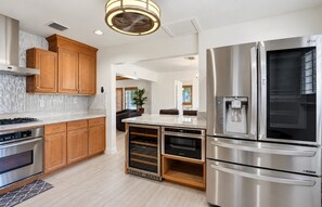 A modern kitchen with stainless steel appliances, wooden cabinets, and a central island. - 4BR Home • Private Pool • Tiki Lounge (Hollywood)