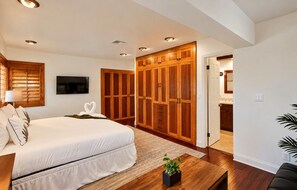 A bedroom with a large bed, wooden wardrobe, a TV, and a small plant on a table. - 4BR Home • Private Pool • Tiki Lounge (Hollywood)
