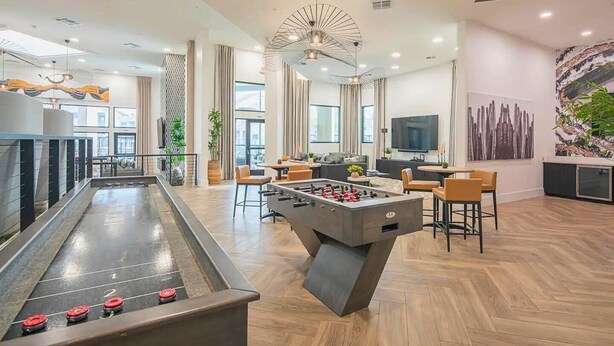 Een moderne ruimte binnenshuis met een tafelvoetbal tafel, zithoek en een pooltafel.