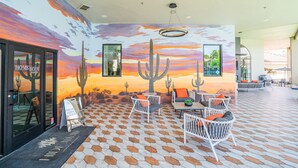 Restaurante com um mural de arte sobre sobremesas, mesas ao ar livre e vista para o pôr do sol.
