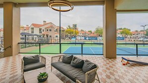 Ein Balkon mit Blick auf einen Tennisplatz und Gebäude.