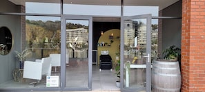 A modern building with large glass doors, a seating area with chairs and a table, and a view of a residential area. - Modern Sleeps 2 Apartment Waterfall Views (Cape Town)