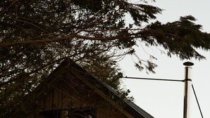 Una cabaña de madera con balcón, chimenea y guirnaldas de luces.