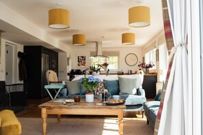 A cozy living room with a wooden coffee table, a sofa, and a kitchen area in the background.