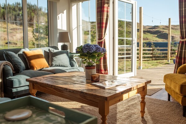 A living room with a wooden coffee table, a sofa, and a potted plant.