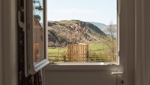 Una habitación con vista a un paisaje rural, una cerca de madera y una silla.
